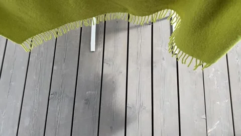 Green blanket swaying gently on deck breeze Видео 343864732