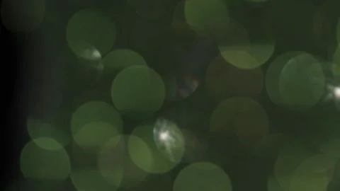 Green bokeh light with a bright light spot leaking into the blackness Vidéo 319390856
