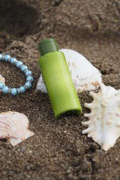 Green bottle placed on sandy beach with seashells Stock Photos