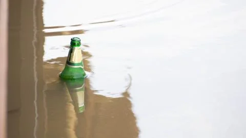 Green bottle was left floating in the river. Fotos de archivo
