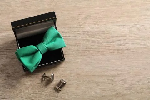 Green bow tie in box with silver cufflinks on wooden surface Stock Photos