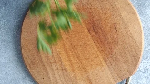 Green branches of parsley are placed on a wooden cutting board to prepare season Video stock 172181357