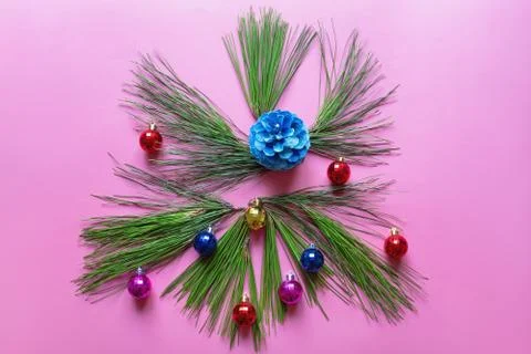 Green branches of pine tree and Christmas balls on pink paper background Stock Photos