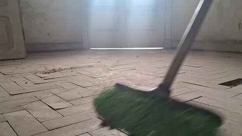 Green bristled broom sweeping dusty wooden floor in motion video clip Stock Footage 339247341