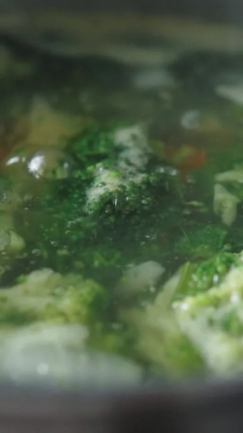 Green broccoli florets and vegetables boiling in bubbling soup pot Stock Footage 346397023