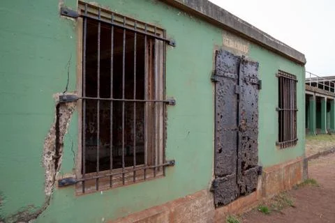 Green broken down building with rusted metal gates and doors Stock Photos