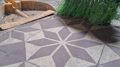 Green broom sweeping dust across patterned tiled floor video footage Stock Footage 339302135