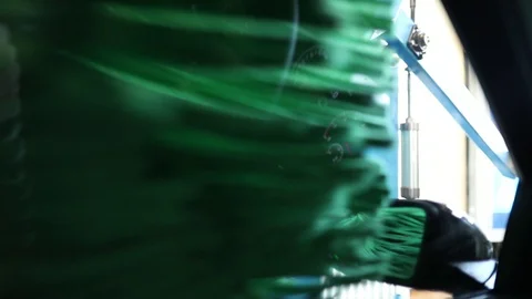 Green brushes rotate behind the side window of the car in the car wash Stock Footage 129709724