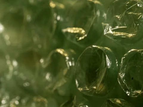 Green bubble wrap glows under warm light Stock Photos