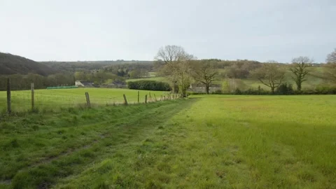Green, bucolic path between fields in the spring countryside, Yorkshire, England Stock Footage 291870969