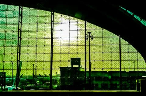 A green building with a large window that is partially covered by a green s.. Stock Photos
