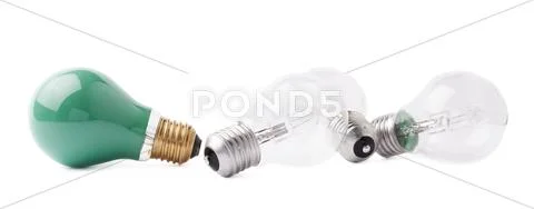 Green bulb lying next to couple of transparent bulbs over white isolated Stock Photos