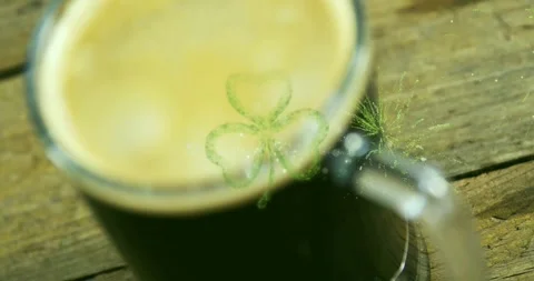 Green burst appearing, particles forming clover on dark mug showing surface Vidéo 329471184