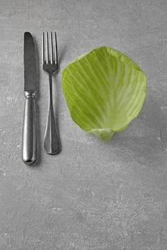 Green cabbage leaf and fork with knife on grey concrete table Stock Photos