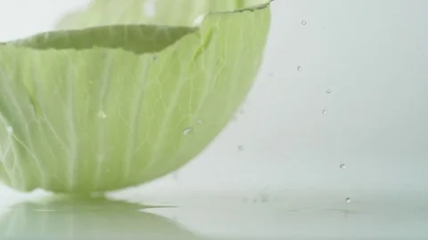 A green cabbage leaf rolling on water surface. Slow Motion. Stock Footage 79478973