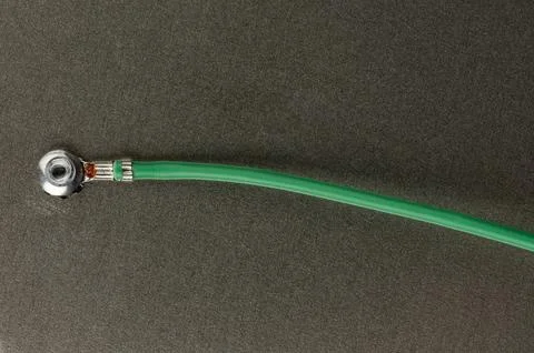 Green cable connected to a metal fitting on a dark surface Stock Photos
