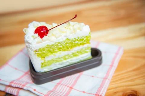 Green cake slice with cherry fruit and cream on white palte on the table - De Foto stock