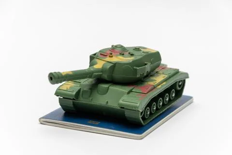 Green camouflaged toy tank displayed on blue notebook isolated on white Stock Photos