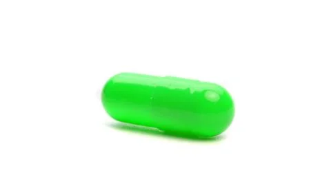 Green capsule isolated on a white background. Stock Photos