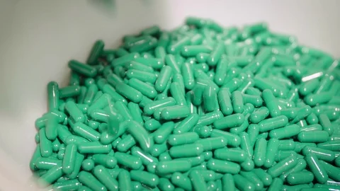 Green capsule pills falling in the white bowl from pharmaceutical dust collector Stock Footage 102460224