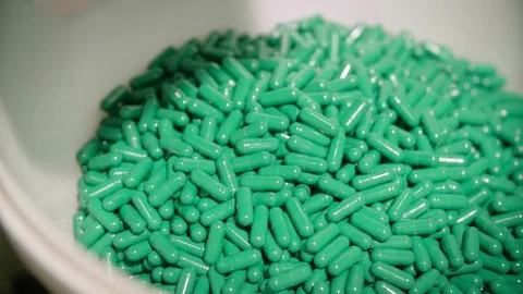 Green capsule pills falling in the white bowl from pharmaceutical dust collector Stock Footage 102465770