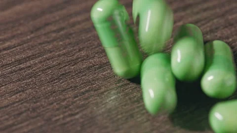 The green capsules are falling onto the table Stock Footage 270413254