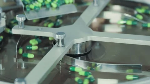 Green capsules fall from above onto a rotating metal surface in slow motion.. 스톡 동영상 240562071