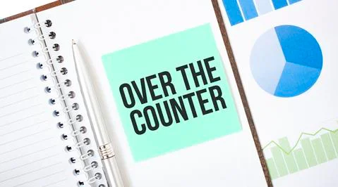 Green card on the white notepad. Text OVER THE COUNTER Business concept Stock Photos