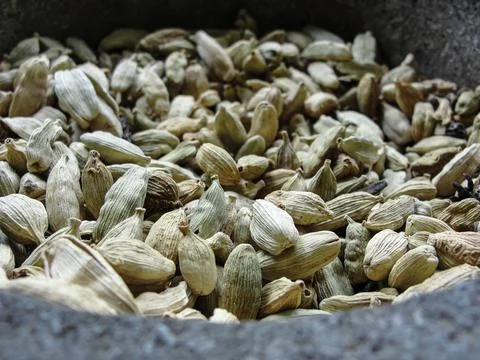 Green cardamom grains in a large stone mortar Stock Photos