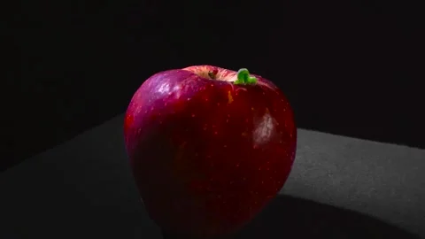Green Caterpillar Crawling on Red Apple Against Black Background Stock Footage 332628823