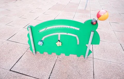A green caterpillar-shaped interactive play panel on a rubber-tiled playgroun Foto stock