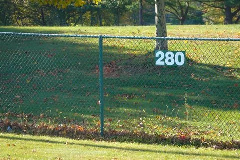 Green chain link fence in a grassy field with a sign that says 280 Stock Photos