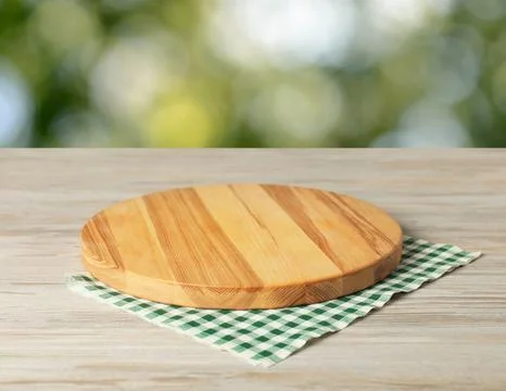 Green checkered tablecloth and board on wooden table outdoors, closeup Stock Photos