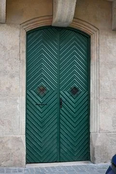 Green chevron-patterned double door in a stone facade Stock Photos