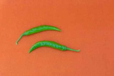 Green chilli in a orange background Stock Photos