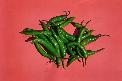 Green Chilli spice vegetables on red background Stock Photos