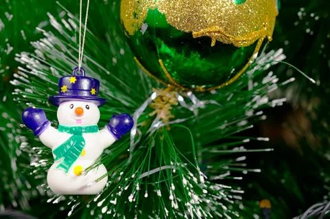 Green Christmas tree with bright colored glass balls and snowman. Stock Photos