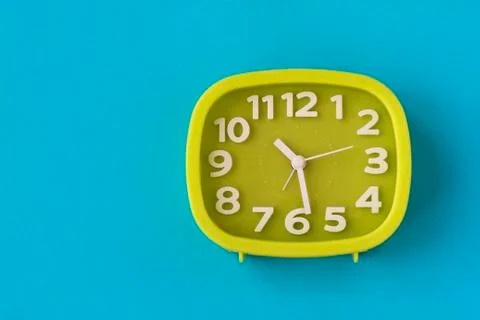 Green clock with white numbers and arrows on blue background Stock Photos