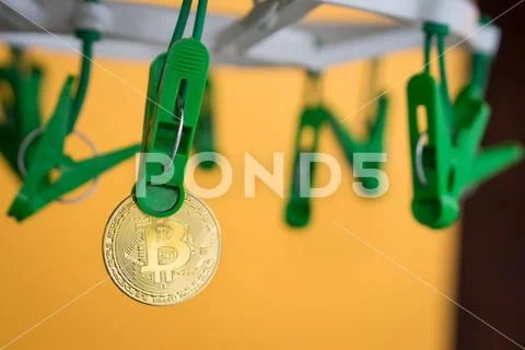 Green clothes peg hold one gold Bitcoin Stock Photos