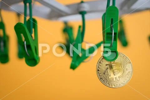 Green clothes peg hold one gold Bitcoin Stock Photos