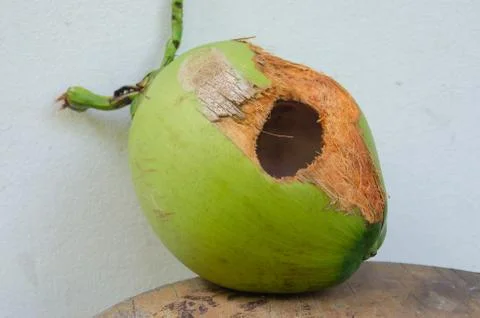 Green coconut with hole on table Stock Photos