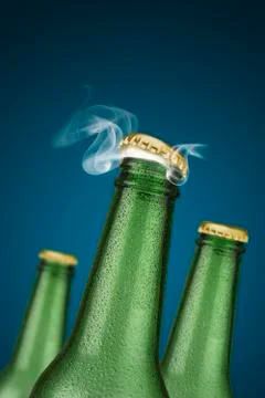 Green cold beer bottles with water drops and golden cap open on blue background Foto stock