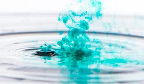 Green colored water drop splashing in clear water.. Stock Photos