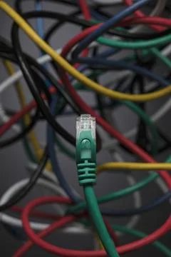 Green computer cable over chaotic, tangled contrasting multicolor computer cable Fotos Stock
