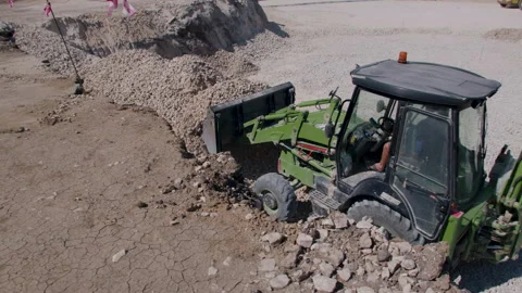 Green construction tractor that loads the stone from one mound and transports Stock Footage 202884562