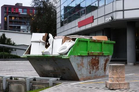 A green container for construction waste filled with debris, including old .. Stock Photos