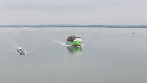 Green container ship gliding smoothly across calm gray water stacked Stock Footage 328204527