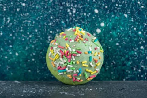 Green cookie with sprinkles on blue background Stock Photos