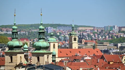 Green copper onion domes and a church clock tower above red tiled rooftops, with Stock Footage 342329735