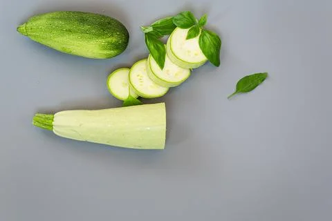 Green courgette with fresh basil on clean gray background Stock Photos